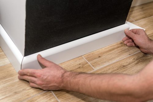 Close,Up,Of,Mans,Hands,Installing,Skirting,Board